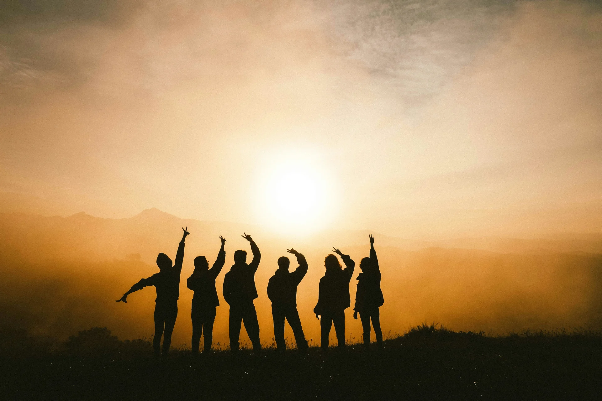 Enkele jongeren samen met op de achtergrond een mistige zonsondergang