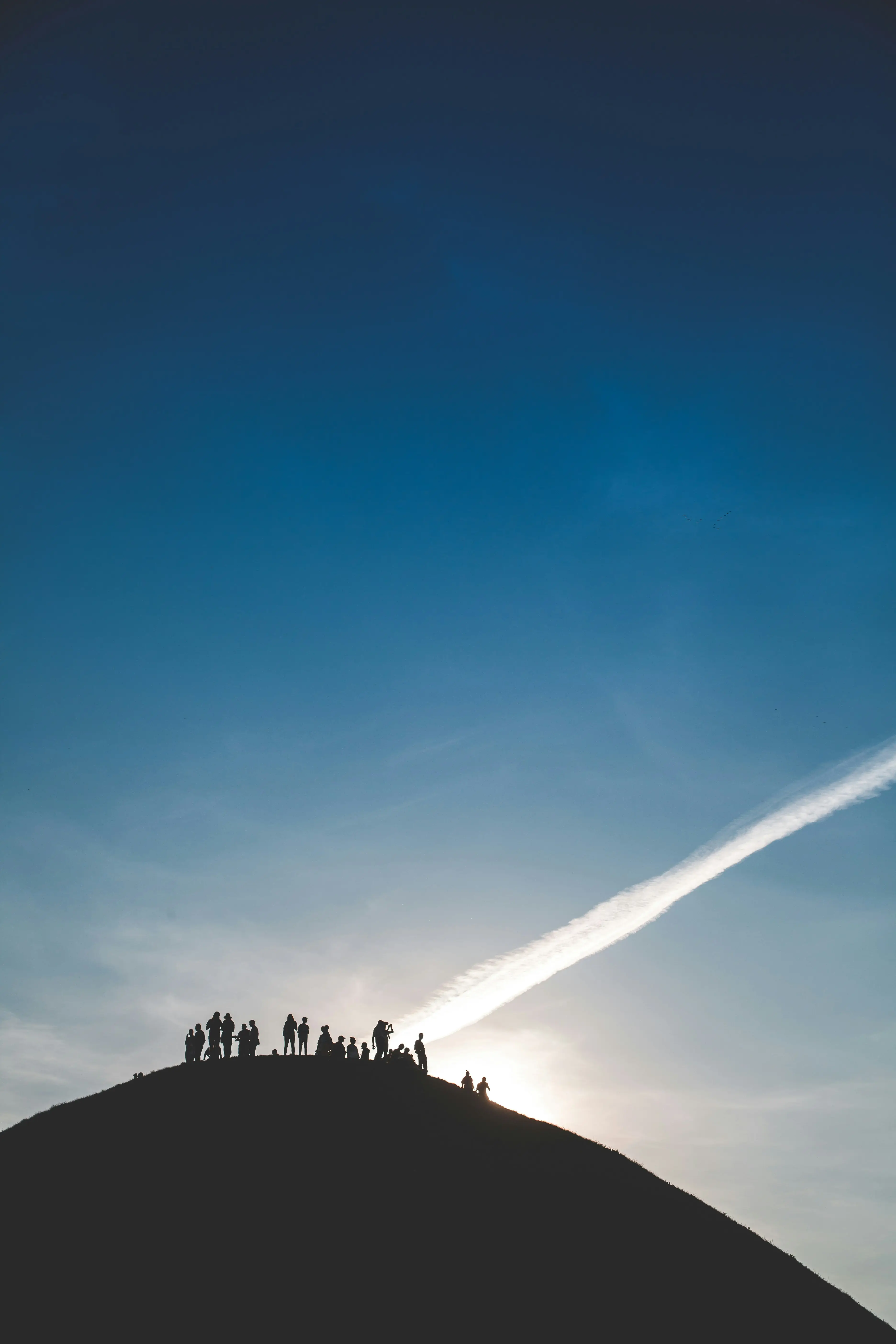 een groep mensen die bij een zonsondergang op een bergtop staan