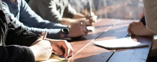enkele mensen met een notitieblok die aan tafel zitten 